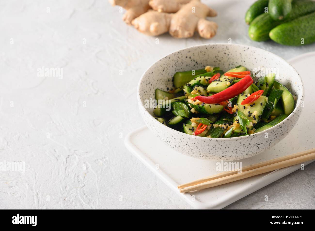 Asiatisch würziger Salat gebrochene Gurken mit frischem Koriander, Ingwer auf weißem Hintergrund. Beliebte chinesische kalte Vorspeise. Nahaufnahme. Stockfoto