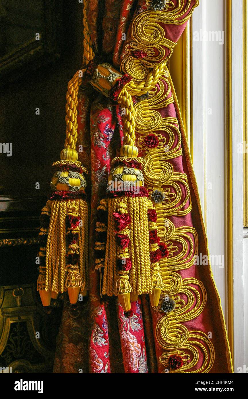 Nahaufnahme von roten und goldenen Brokatvorhängen mit passender tasselierter Krawatte, Chatsworth House, Derbyshire, Großbritannien Stockfoto