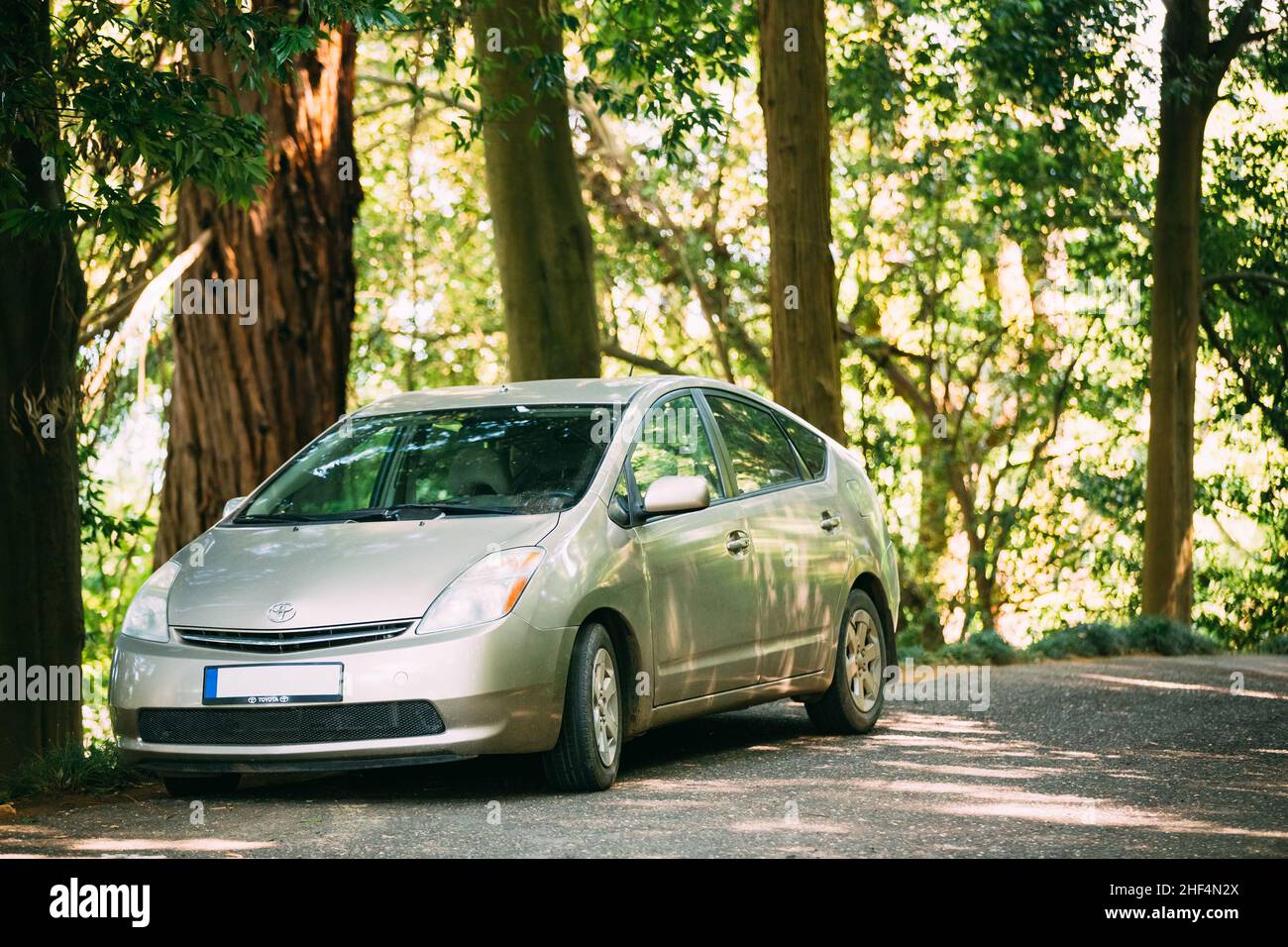 Toyota Prius ist ein voll Hybrid-Elektro-Auto wird auf Landstraße im Wald im Schatten der Bäume geparkt Stockfoto