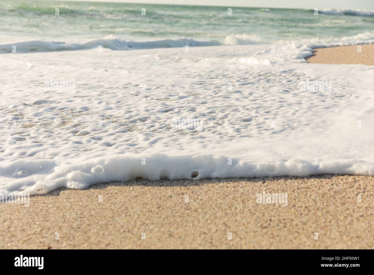 Weißer Meeresschaum mit Wellengang am Strand an sonnigen Tagen Stockfoto