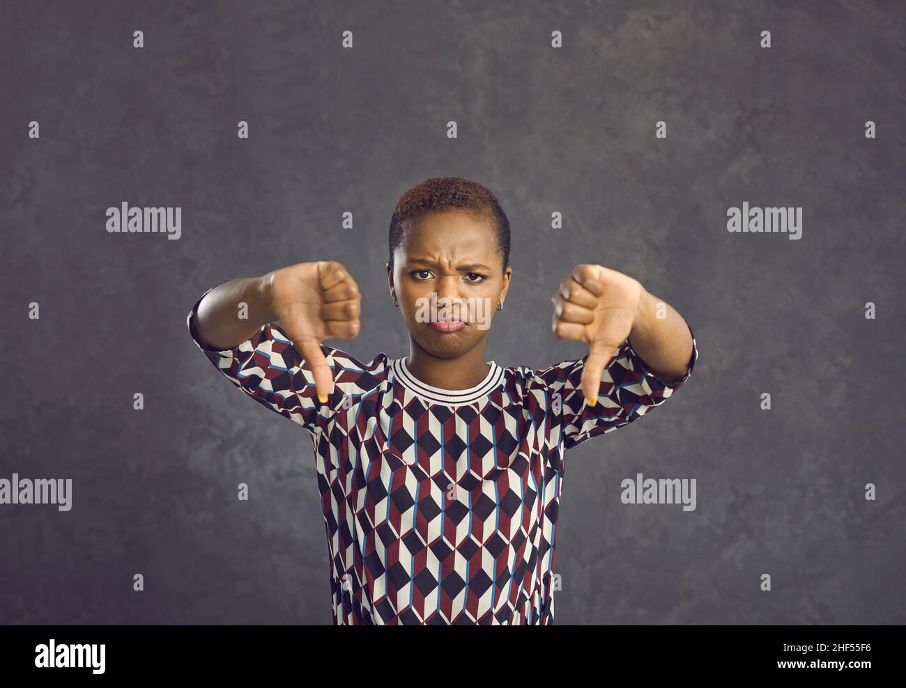 Unglücklich enttäuschte junge afroamerikanische Frau, die mit beiden Händen Daumen nach unten gab Stockfoto