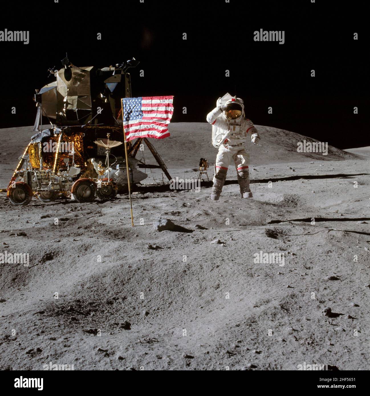 Astronaut John W. Young, Kommandant der Mondlandemission Apollo 16, springt von der Mondoberfläche, als er die Flagge der Vereinigten Staaten begrüßt. Stockfoto