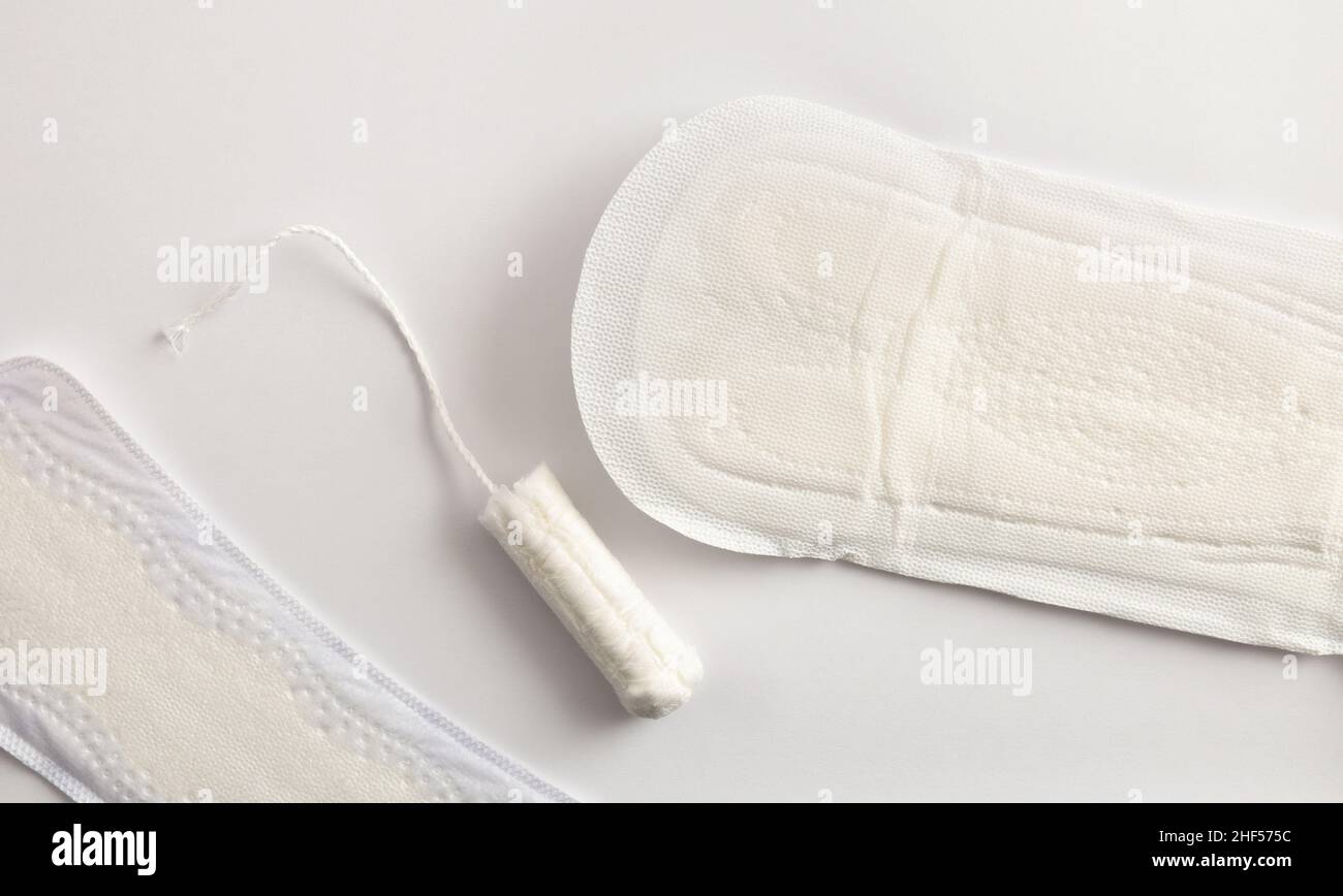 Hintergrund mit weiblichen absorbierenden Protektoren für den Menstruationszyklus. Pantiliner und Tampon auf weißem Hintergrund. Draufsicht. Horizontale Zusammensetzung. Stockfoto