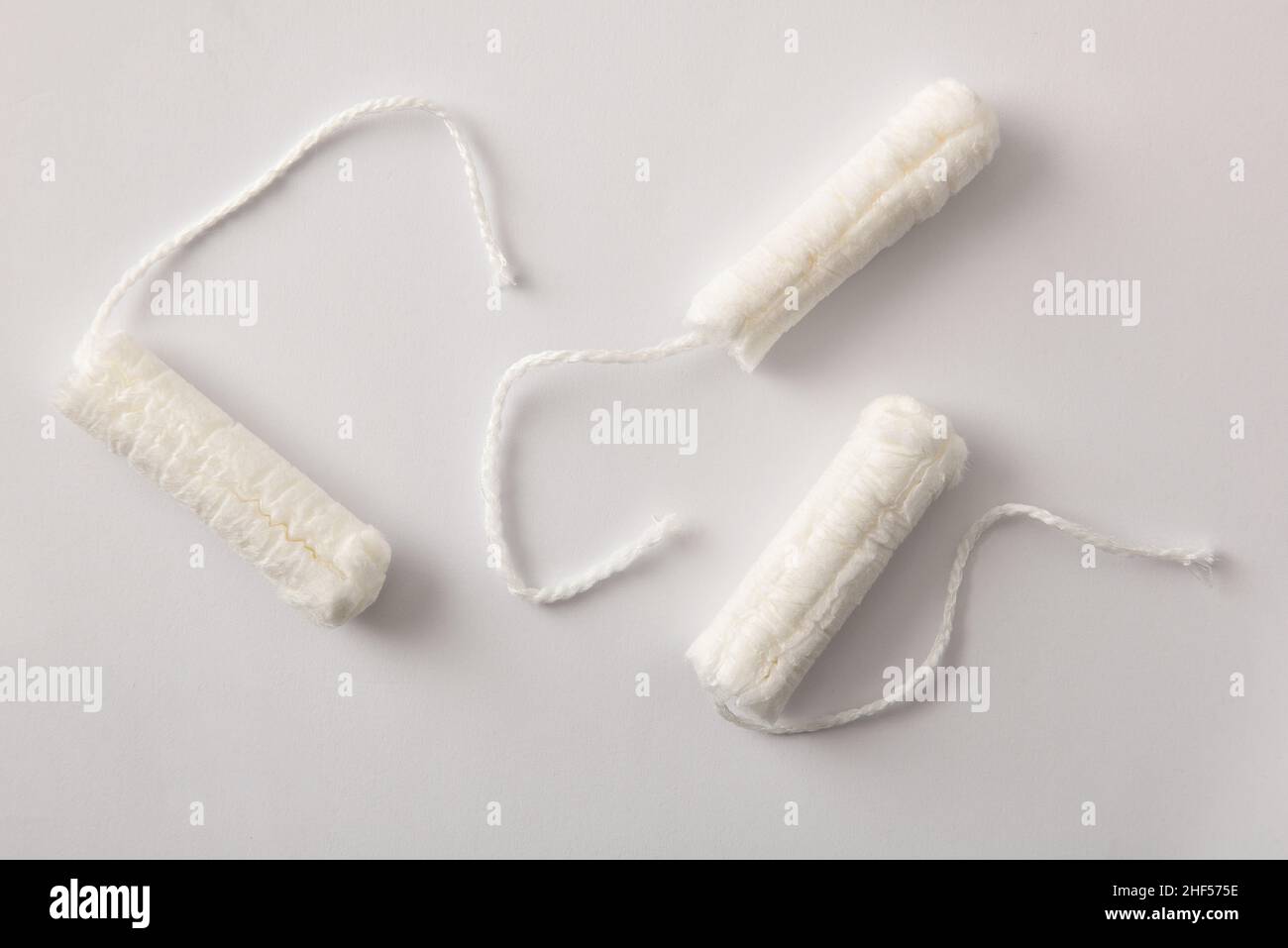 Drei weiche, schützende und saugfähige Tampons aus Baumwolle für die Damenpflege auf weißem Hintergrund. Draufsicht. Horizontale Zusammensetzung. Stockfoto