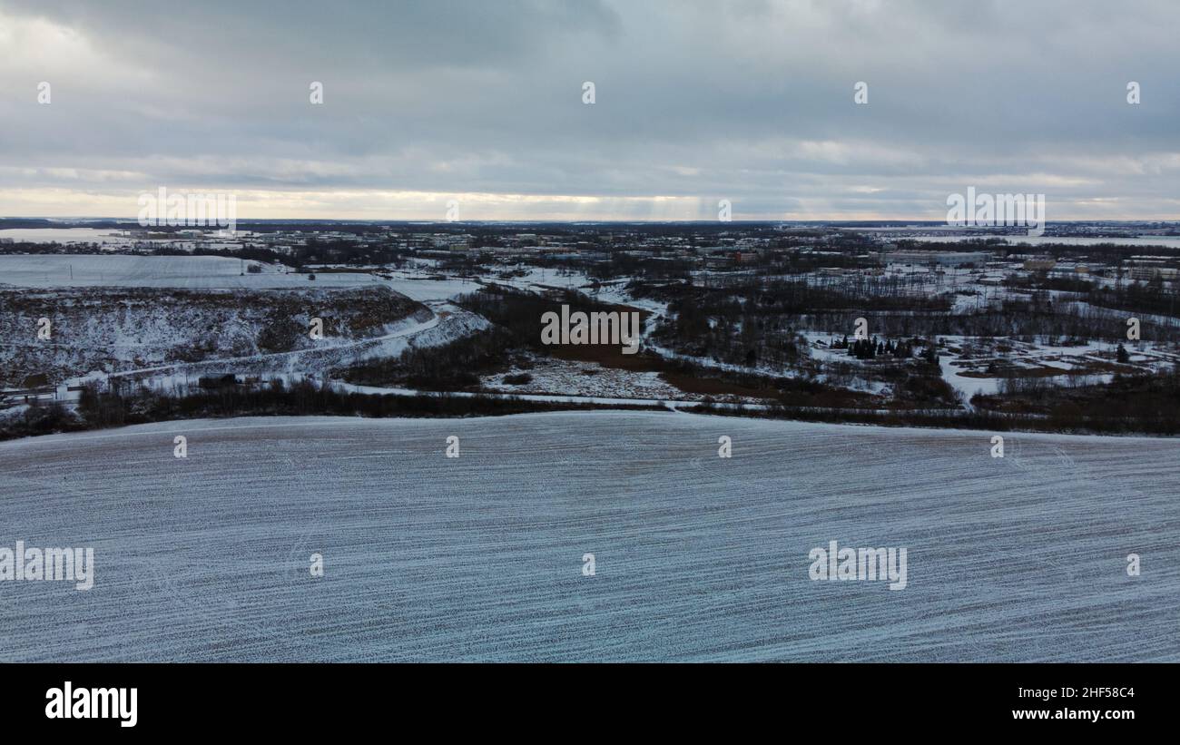 Fliegen über ein schneebedecktes Feld. Spuren der landwirtschaftlichen Bodenbearbeitung sind unter dem Schnee sichtbar. Luftaufnahmen. Stockfoto