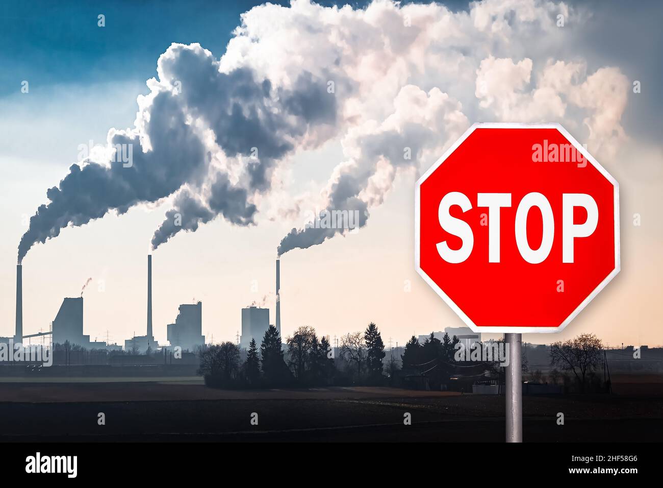 Rotes Stoppschild vor den Rauchstapeln eines Kohlekraftwerks Stockfoto