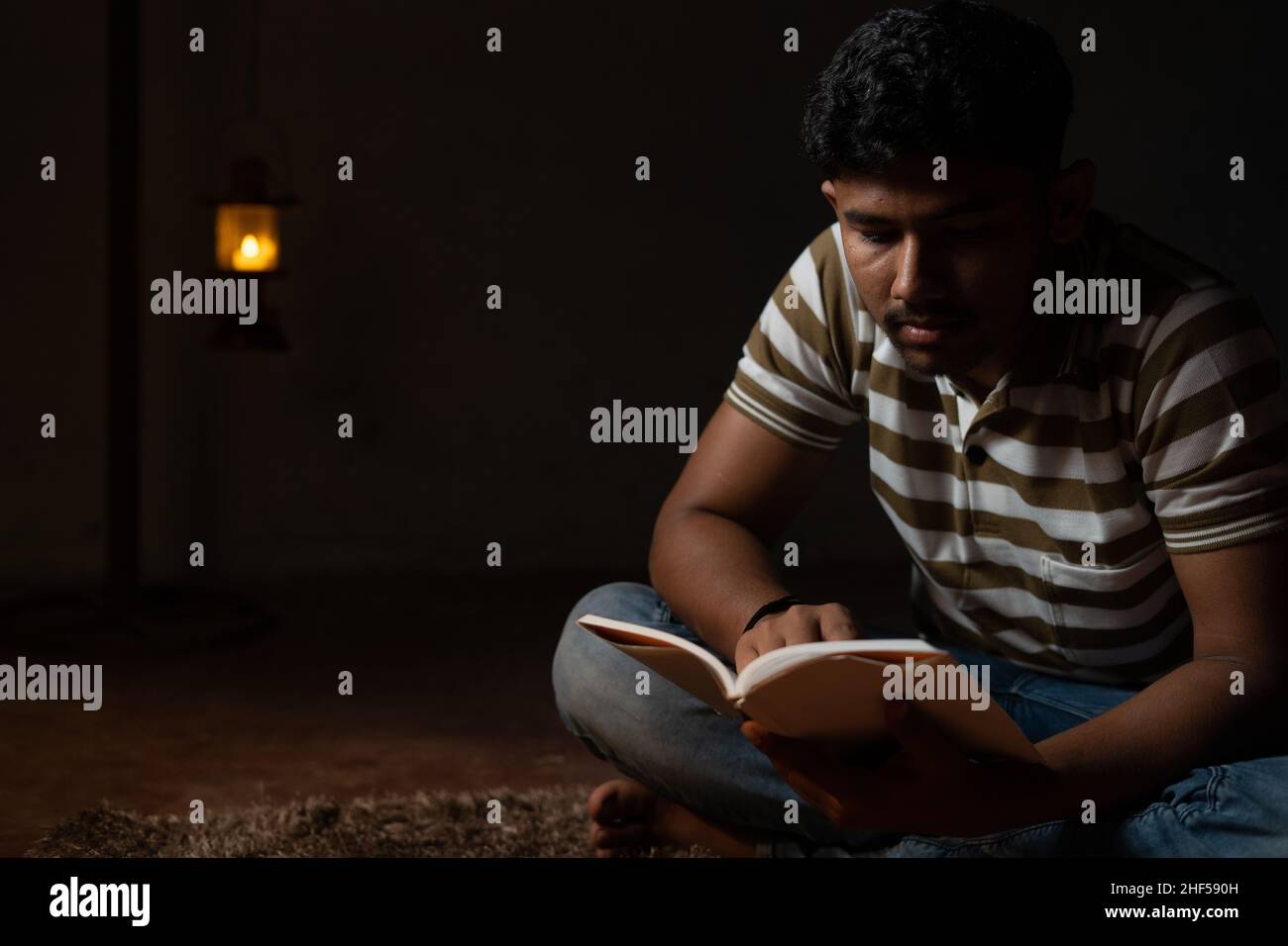 Junge Studenten beschäftigt Lesung während der Nacht unter Öllampe oder Laterne aufgrund von Stromausfall und Armut - concpet von Stromausfall, Blackout während der Prüfung. Stockfoto