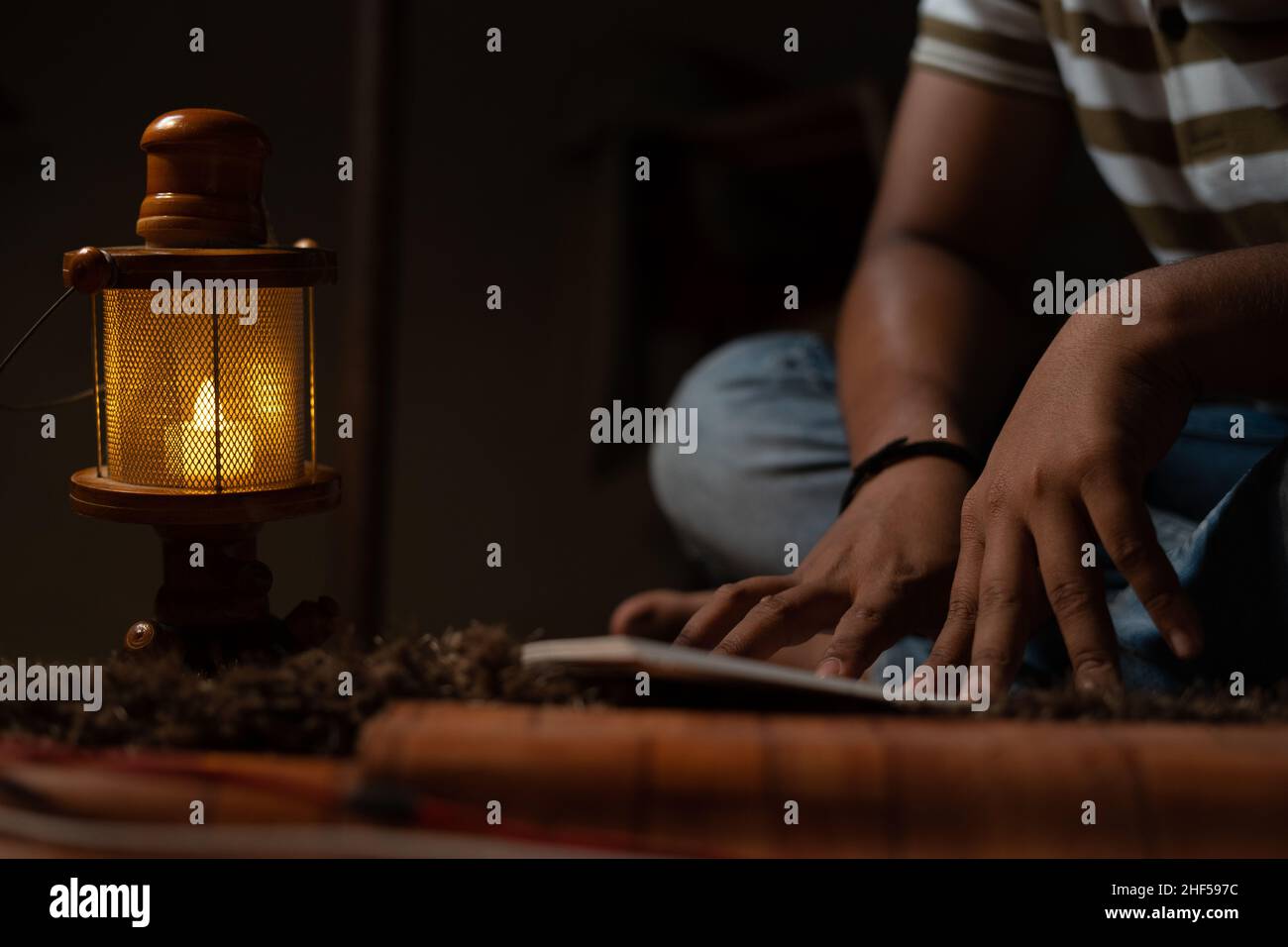 Unkenntlich Junge Schüler beschäftigt Lesung während der Nacht unter Öllampe oder Laterne aufgrund von Stromausfall und Armut - concpet von Stromausfall, Blackout Stockfoto