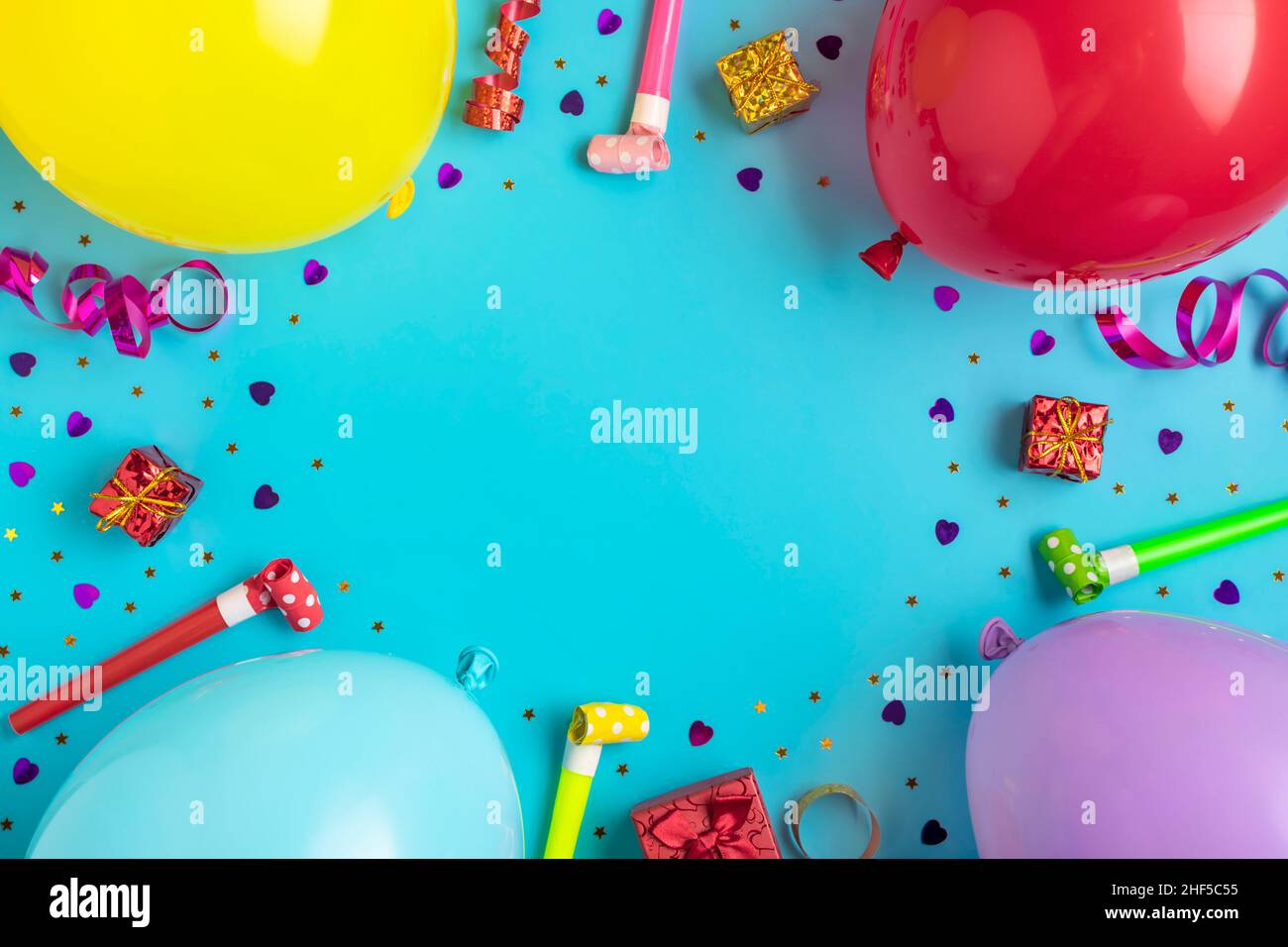 Bunte Party-Rahmen mit roten Geschenk-Box mit verschiedenen Partei Konfetti, Luftballons, Luftschlangen, Pokers und Dekorationen auf blauem Hintergrund. Urlaubskarte flach Stockfoto