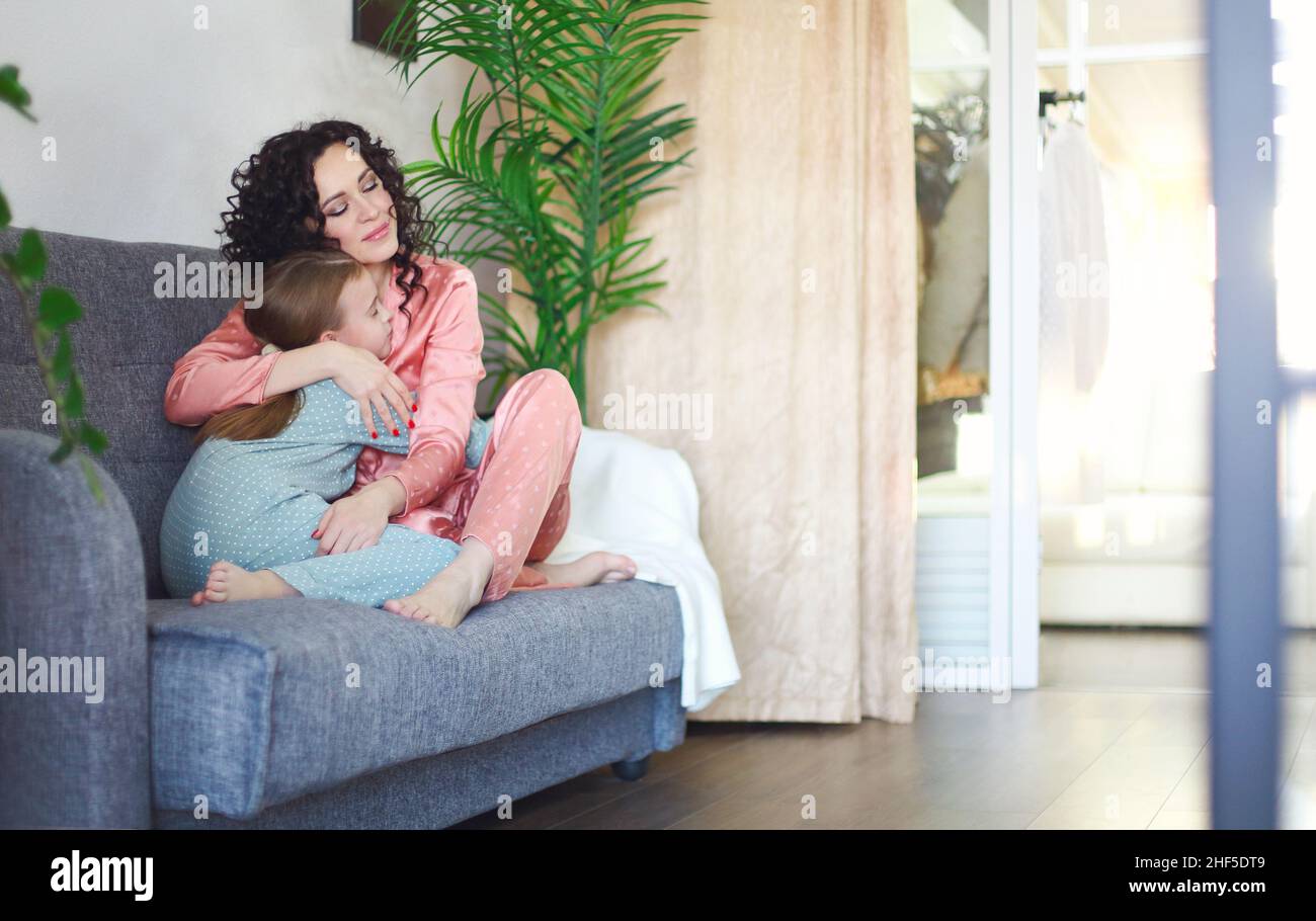 Gemütliches häusliches Foto von glücklicher Mutter und Tochter im Pyjama entspannen auf dem Sofa am Morgen, junge schöne Mutter und kleines Mädchen Kind faul verbringen Familie Stockfoto