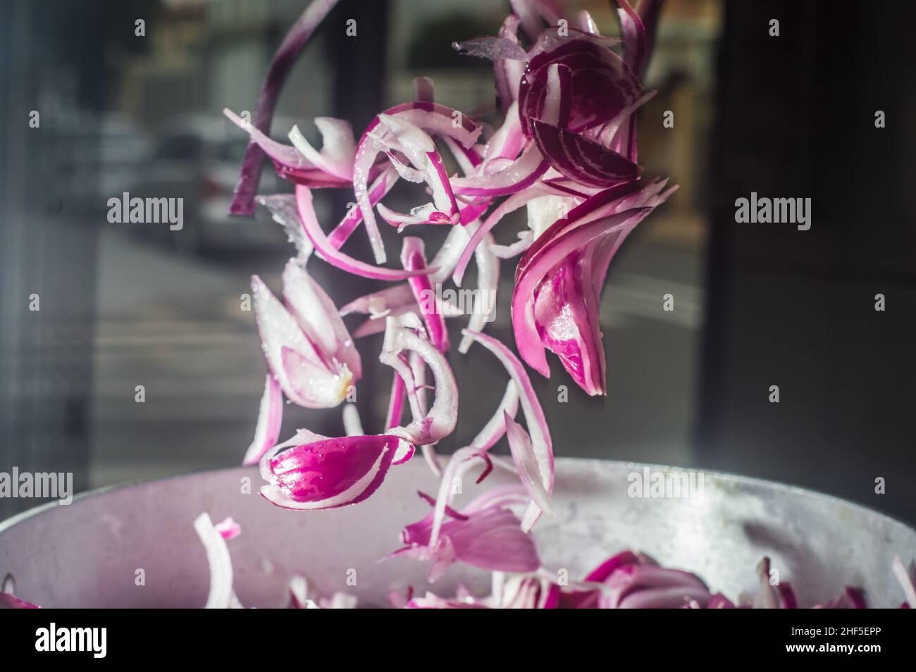 Rote Zwiebel in einer Aluminiumpfanne, Straße im Hintergrund Stockfoto