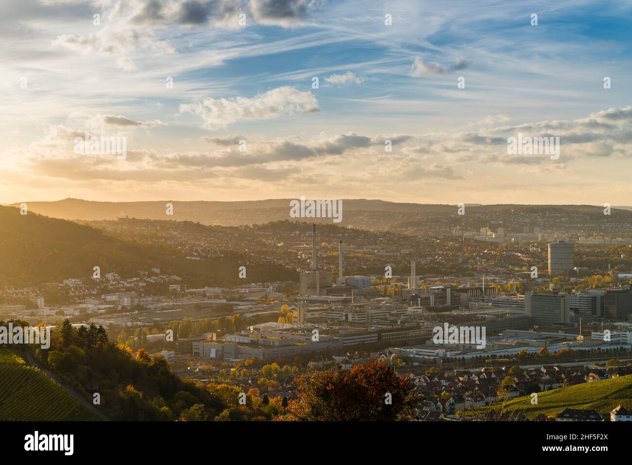 Deutschland, Stuttgart Stadtpanoramallandschaft Blick über Industrieviertel und Berge, Häuser, Straßen bei Sonnenuntergang in warmem orangefarbenem Licht Stockfoto