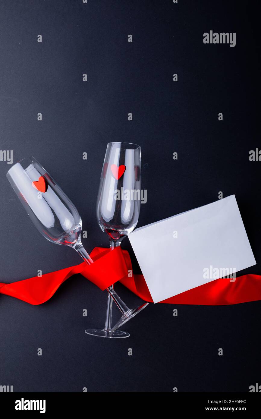 Leere Sektflöten mit rotem Band durch Umschlag isoliert auf grauem Hintergrund gebunden, kopieren Raum Stockfoto