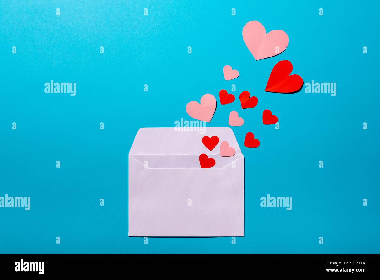 Direkt über der Aufnahme von Herzen, die aus dem Umschlag über blauem Hintergrund kommen, kopieren Sie den Raum Stockfoto