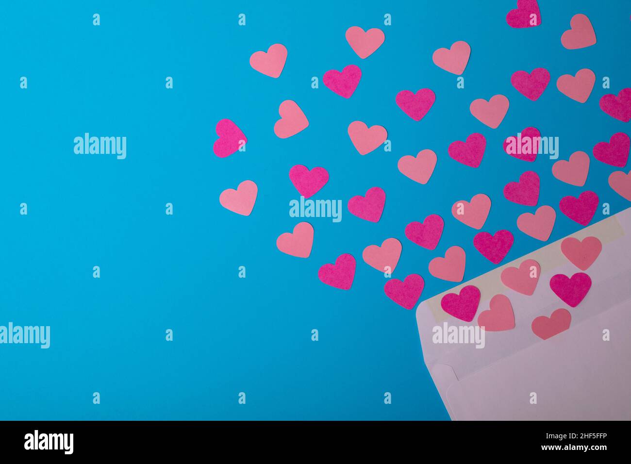 Direkt über der Ansicht von rosa Herzen, die aus dem Umschlag über blauen Hintergrund kommen, kopieren Sie Platz Stockfoto