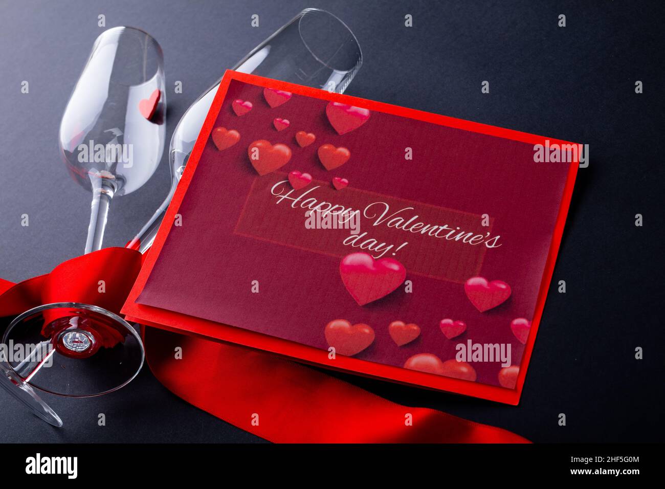 Geschenkkarte mit glücklichen Valentinstag Text von Sektflöten mit rotem Band eingewickelt Stockfoto