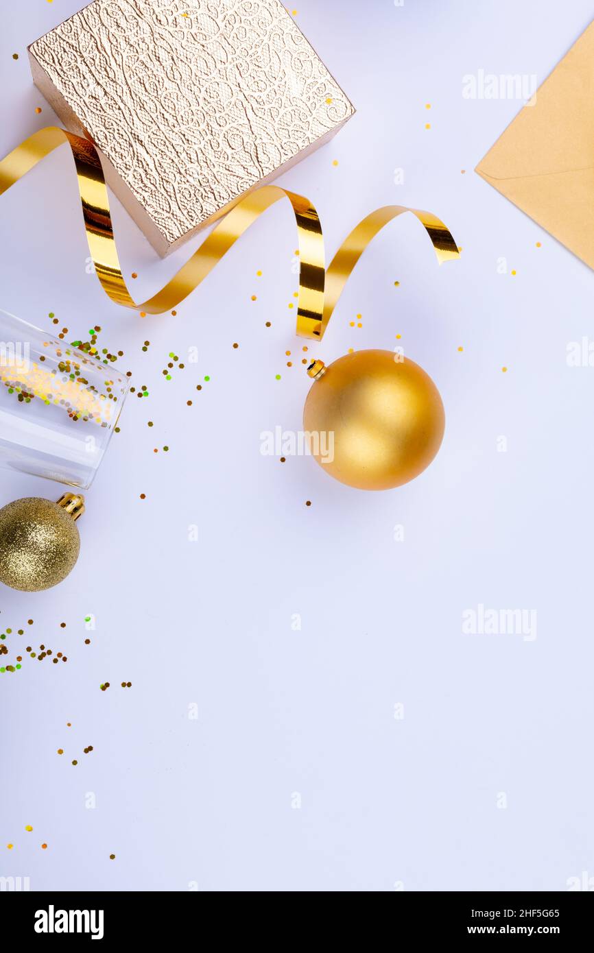 Goldenes Band und Kugeln in Geschenkbox und Sektflöte mit Konfetti auf weißem Hintergrund Stockfoto