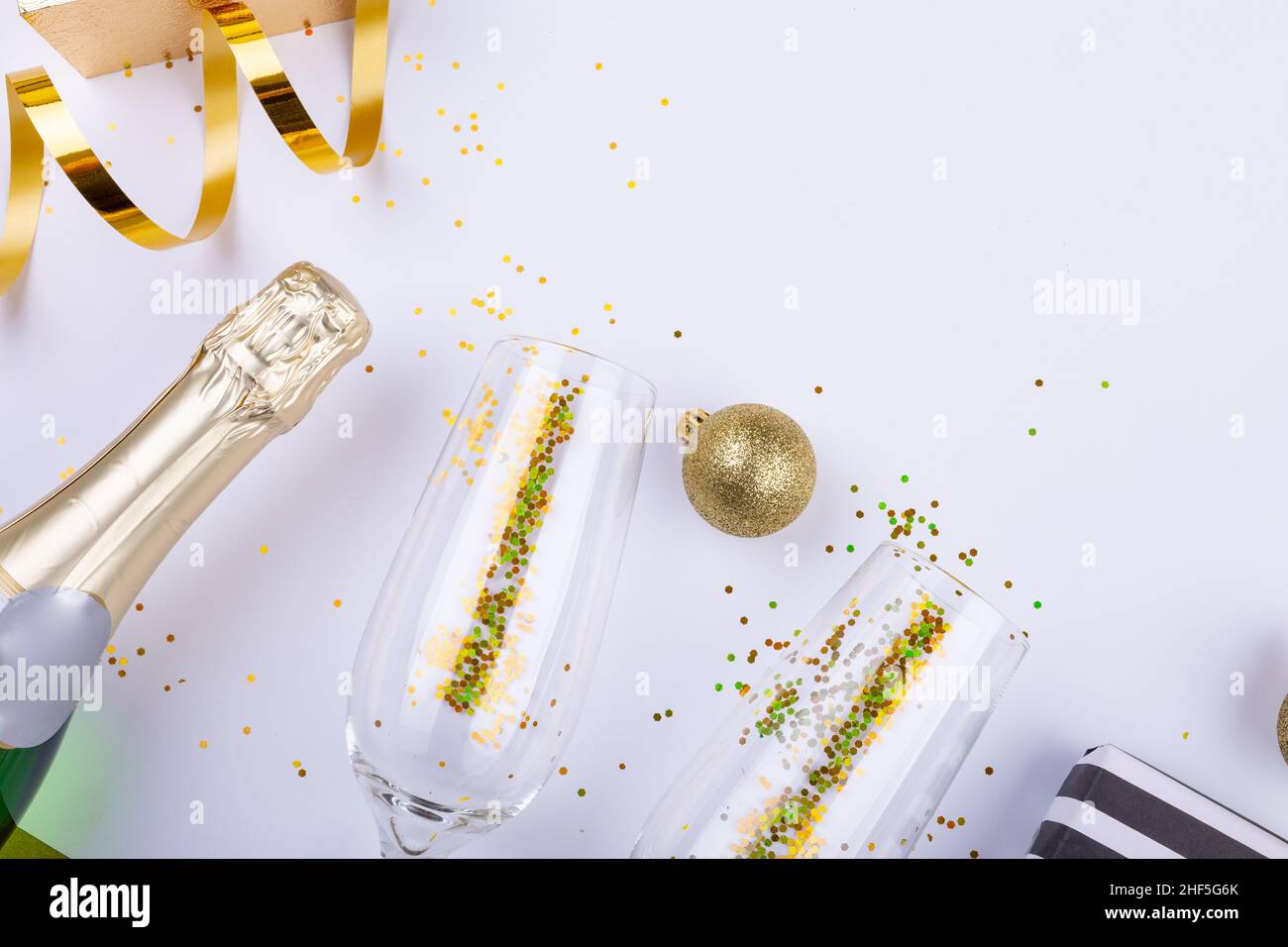 Blick von oben auf eine Champagnerflasche mit Konfetti in Flöten von der dekorativen Kugel Stockfoto