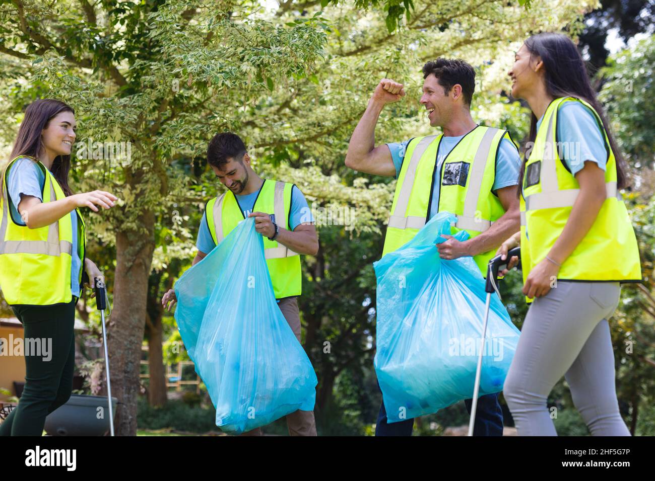 Fröhliche, multirassische Freiwillige sammeln Müll während der Säuberung im Park Stockfoto