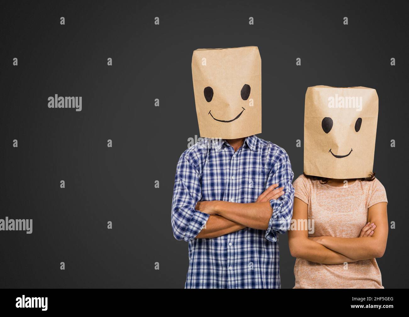Paar in Papiertüten mit Gesichtsemotionen, die gegen den Kopierraum auf grauem Hintergrund malen Stockfoto
