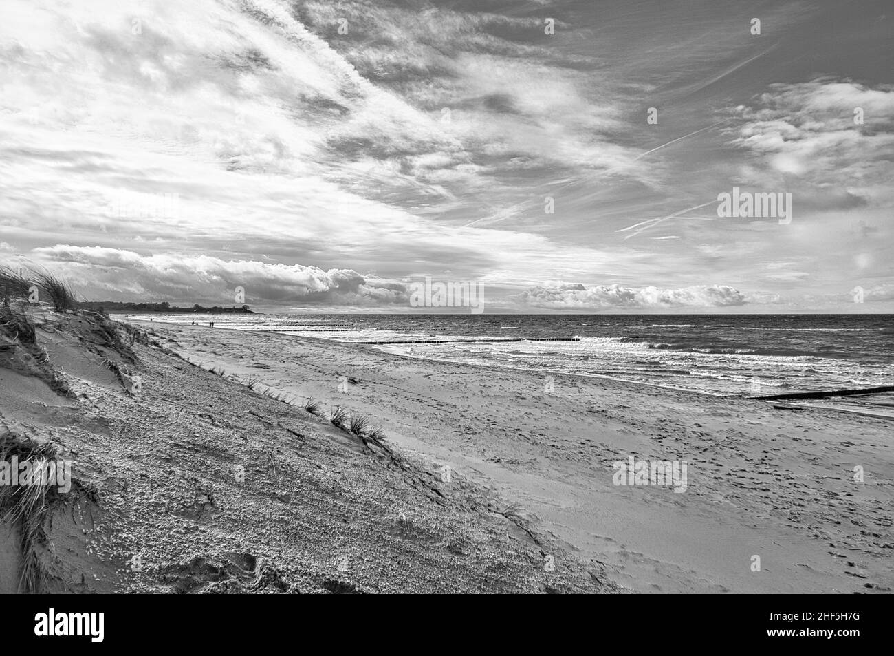Im Frühjahr Blick über den Strand in Zingst an der Ostsee. Spazieren Sie durch das Meer in Schwarz und Weiß. Sich bewegende Wolken am Himmel Stockfoto