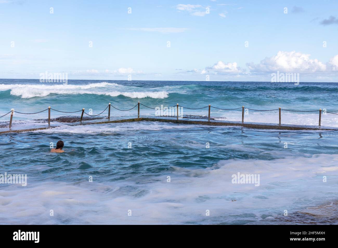Avalon Beach Ocean Pool mit Person, die im Open Water Rock Pool schwimmend ist, Avalon Beach Sydney, Australien Blue Sky Summer Stockfoto