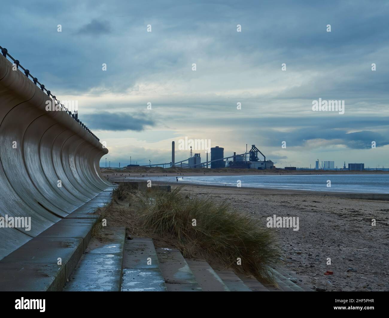 Ein industrieller Horizont; Redcar verlassene Stahlwerke, eingerahmt von einer rekurvigen Meeresmauer. Stockfoto