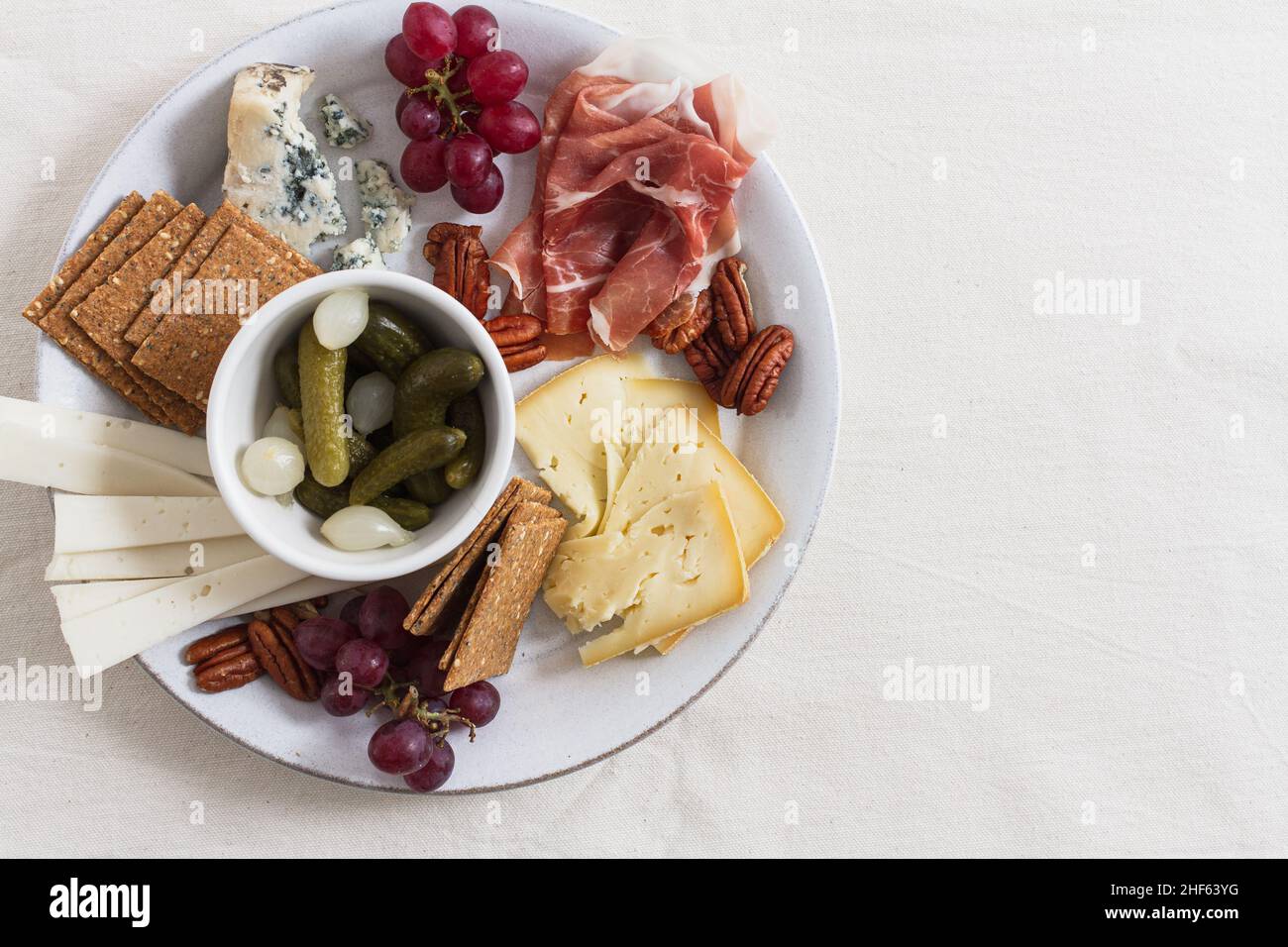 Winterkäseplatte mit einer Auswahl an irischen Käsesorten, Pekannüssen, roten Trauben, Schinken, eingelegten Cornichons und Perlzwiebeln. Stockfoto