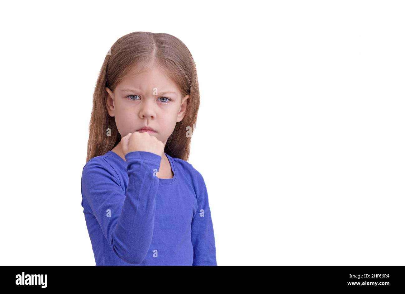 Ernst Kind Kind zeigt Faust isoliert auf weißem Hintergrund Blick auf Kamera Taille bis kaukasischen kleinen Mädchen von 5 Jahren in blau Stockfoto