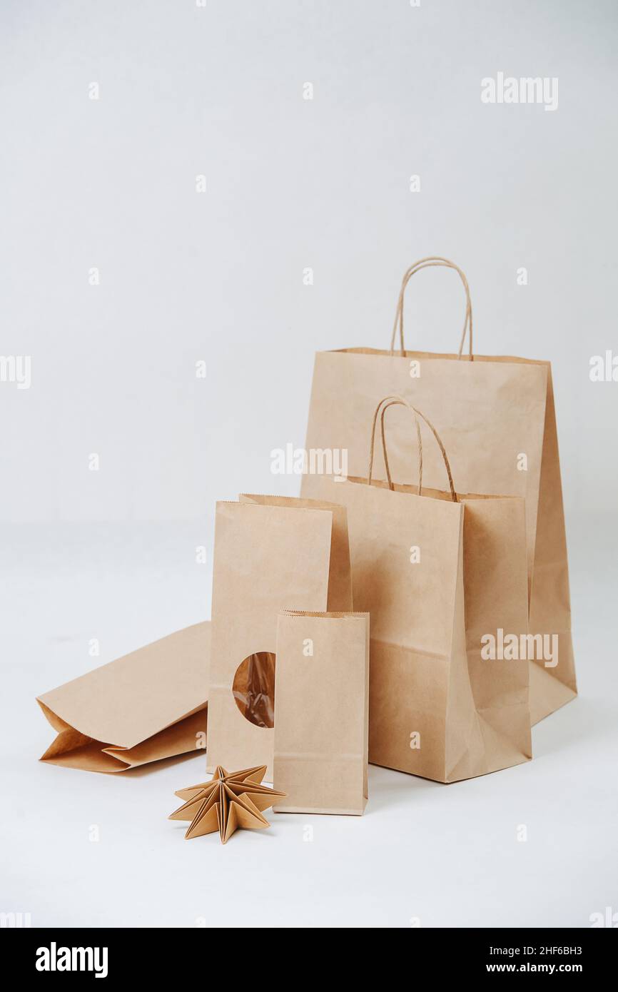 Eine Reihe von Papiertüten, die auf weißem Hintergrund größer werden. Zusammensetzung. Umweltfreundliche kompostierbare Verpackung. Stockfoto
