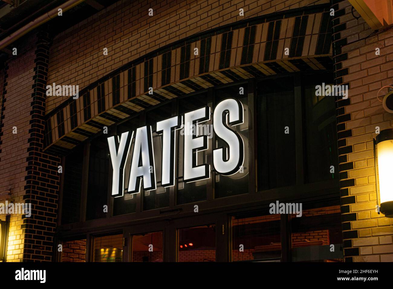 Manchester, Großbritannien - 22nd. September 2019:Yates lebendiges Neonschild am Eingang des Yates Pub, Cocktailbar und Restaurant in der Druckerei in der CI Stockfoto