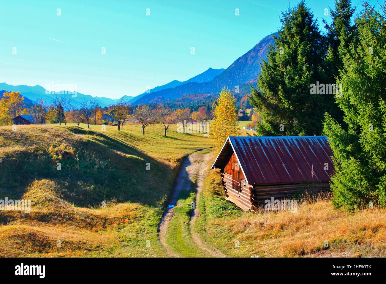 Feldweg in Gerold im Hintergrund eine Wiese Obstgarten, Apfelgarten, Scheune, Weg, atmosphärisch, Gerold, Deutschland, Bayern, Oberbayern, Werdenfelser Land, Klais, blauer Himmel, herbstlich Stockfoto