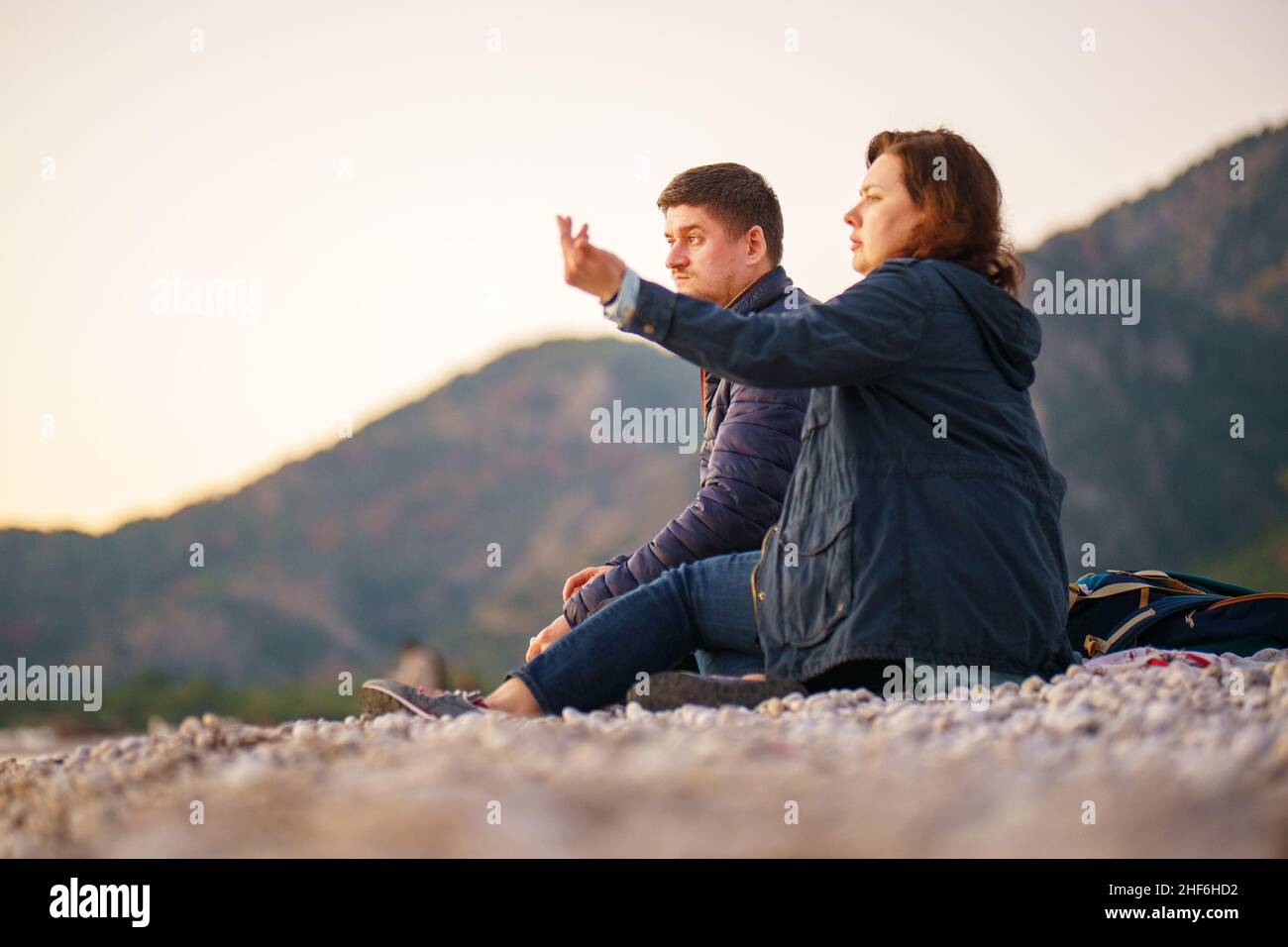 Reisende. Mann und Frau. Datum. Romantik. Ein freier Tag in der Natur. Ein Mann und eine Frau sitzen an einem Steinstrand und genießen das Wintermeer und eine schöne Sonne Stockfoto