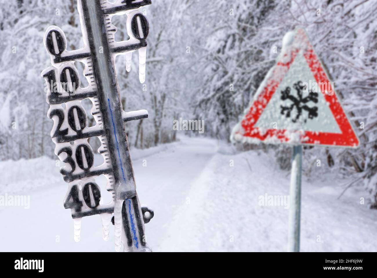 Das Thermometer zeigt kalte Temperaturen und Eiszapfen im Winter auf rutschiger Straße an Stockfoto