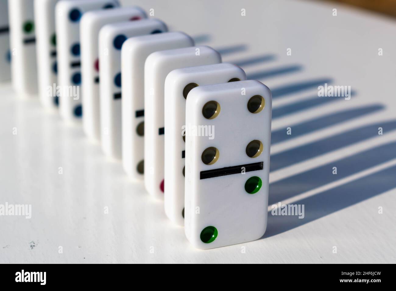 Weiße Domino-Fliesen stehen ordentlich auf einem weißen Tisch, bereit, geschoben oder umgestürzt zu werden. Konzept für Familienspaß und Dominospiele, Organisation, OTC Stockfoto