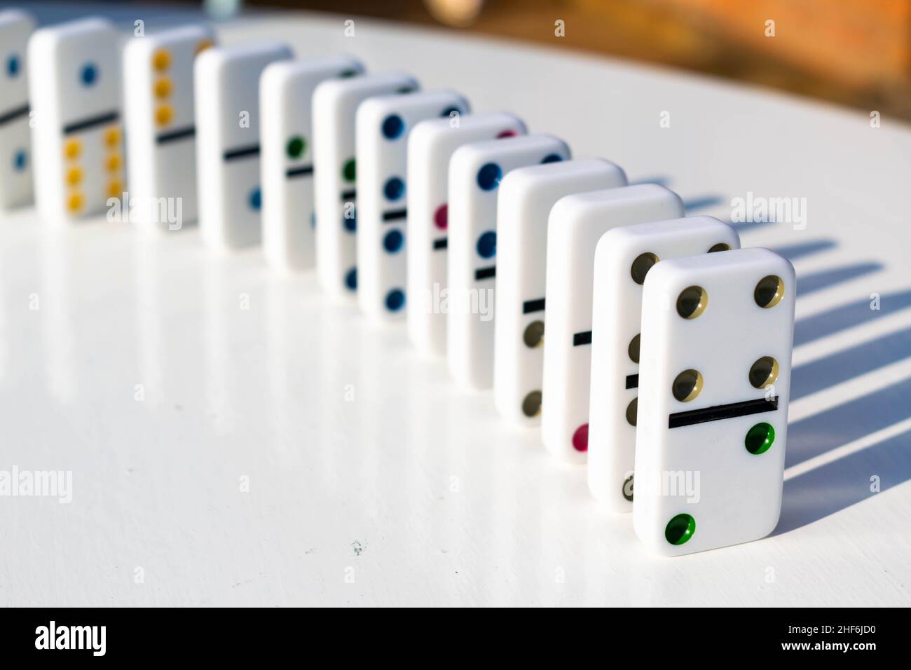 Weiße Domino-Fliesen stehen ordentlich auf einem weißen Tisch, bereit, geschoben oder umgestürzt zu werden. Konzept für Familienspaß und Dominospiele, Organisation, OTC Stockfoto