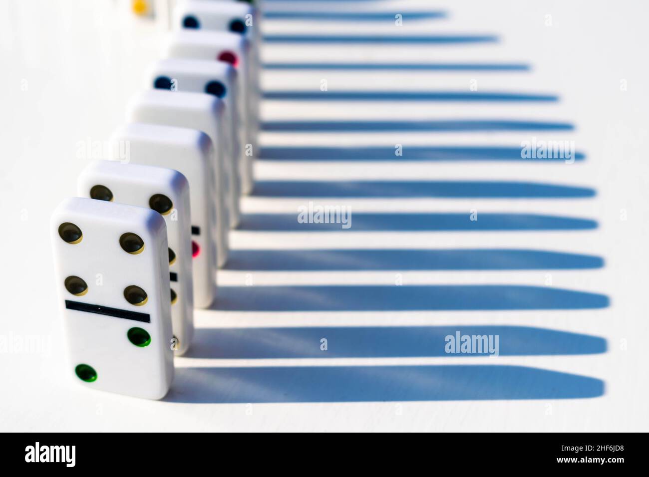 Weiße Domino-Fliesen stehen ordentlich auf einem weißen Tisch, bereit, geschoben oder umgestürzt zu werden. Konzept für Familienspaß und Dominospiele, Organisation, OTC Stockfoto