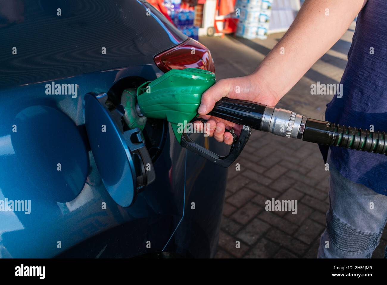 Mann, der die Zapfpistole hält, füllt an einer Tankstelle ein blaues Auto mit Benzin oder Diesel. Steigende Preise für Gas- und Kraftstoffkonzept Stockfoto
