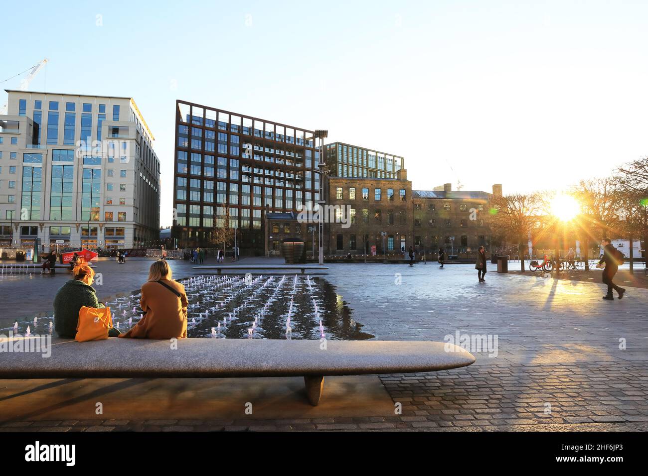 Wintersonne auf einem ruhigen Granary Square nach Plan B Covid-Regeln, mit den Büroblöcken weit darüber hinaus, in Kings Cross, im Norden von London, Großbritannien Stockfoto