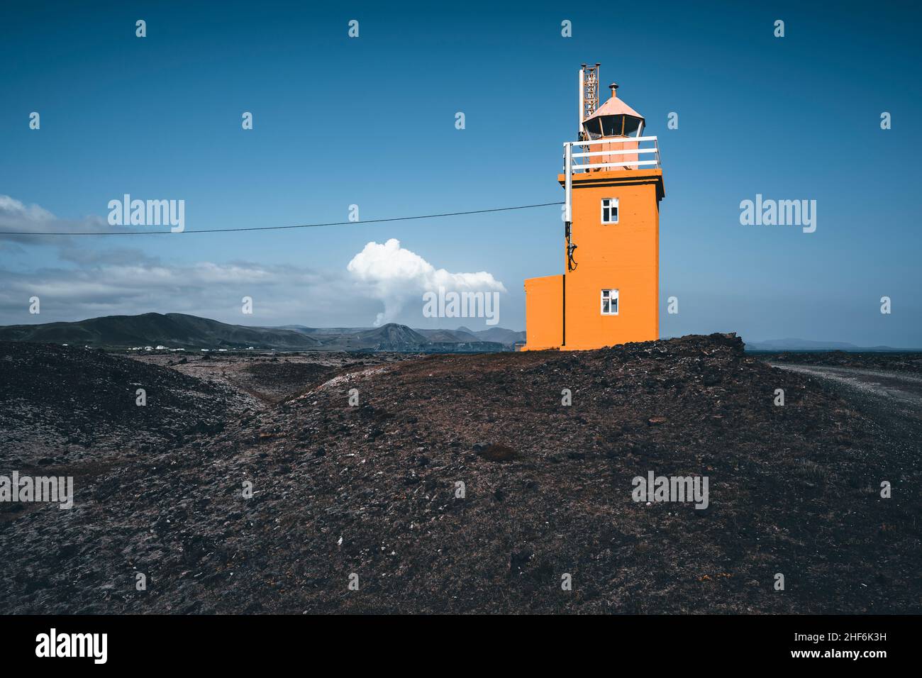 Leuchtturm mit aktivem Vulkan im Hintergrund, Hópsnesviti, Island Stockfoto