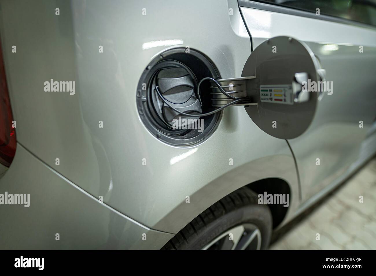 Öffnen Sie den Tankdeckel eines Elektroautos, das bereit ist, mit Ökostrom aufgeladen zu werden Stockfoto