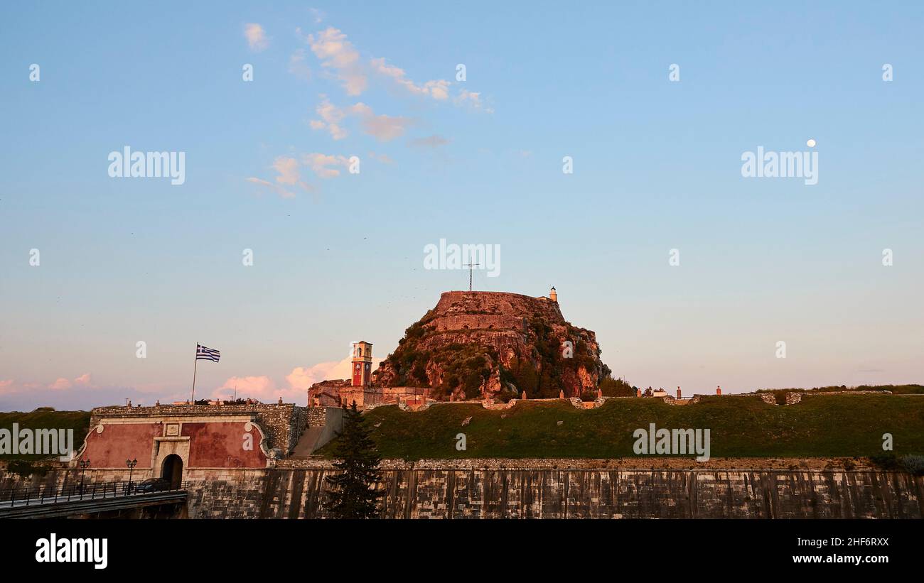 Griechenland, Griechische Inseln, Ionische Inseln, Korfu, Korfu-Stadt, Abendlicht, alte Festung vom Abendlicht beleuchtet, Himmel über hellblau mit einzelnen Wolken, der Vollmond ist oben rechts zu sehen Stockfoto