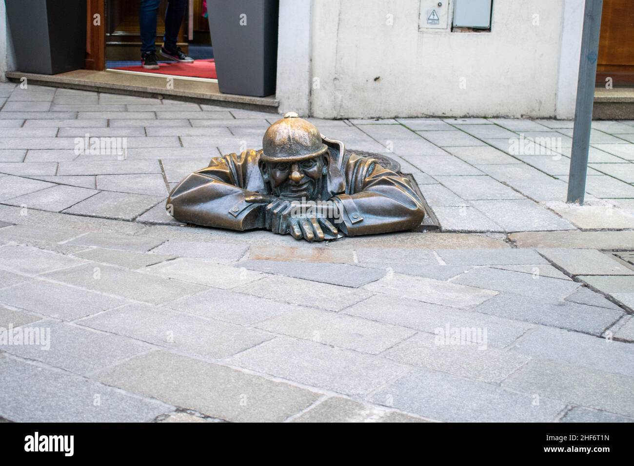 Cumil, die Statue des Mannes bei der Arbeit, aka, der Beobachter. Berühmte Skulptur in Bratislava, Slowenien, die einen Abwasserarbeiter zeigt, der aus einem Schachtloch auf der Passe guckt Stockfoto