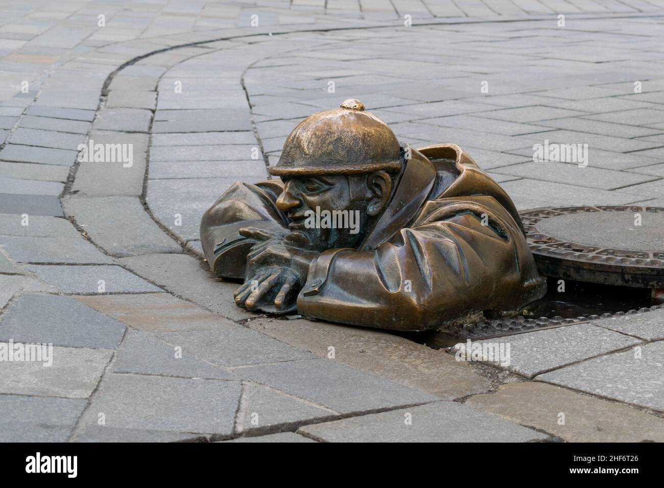 Cumil, die Statue des Mannes bei der Arbeit, aka, der Beobachter. Berühmte Skulptur in Bratislava, Slowenien, die einen Abwasserarbeiter zeigt, der aus einem Schachtloch auf der Passe guckt Stockfoto