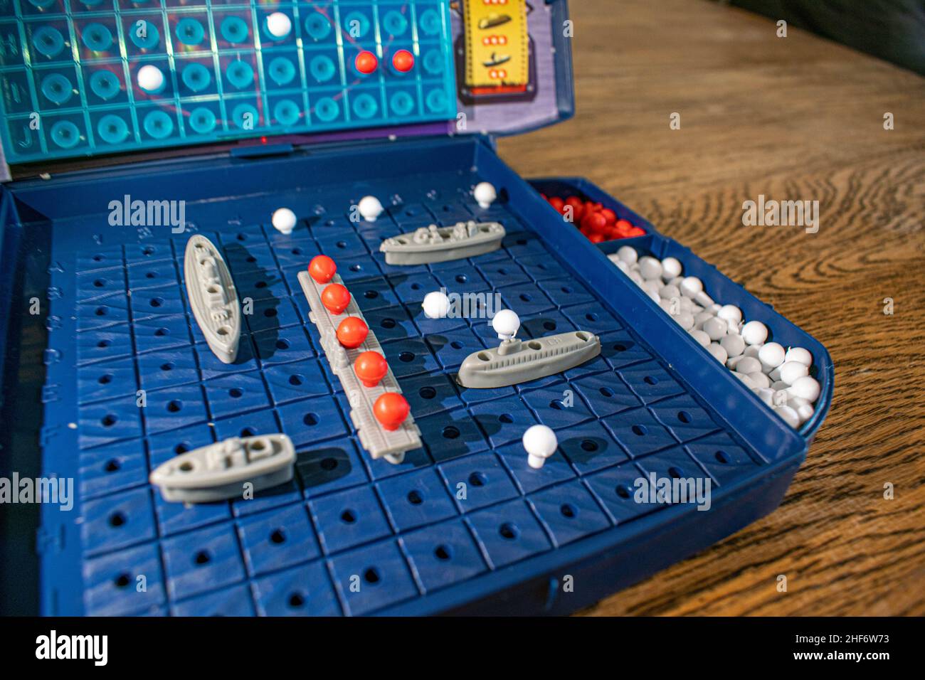 Plastikspielzeug-Kriegsschiffe und U-Boote werden auf dem Spielbrett platziert, das den Ozean darstellt. Der andere Spieler versucht, Ihre Boote im Spiel Batt zu versenken Stockfoto