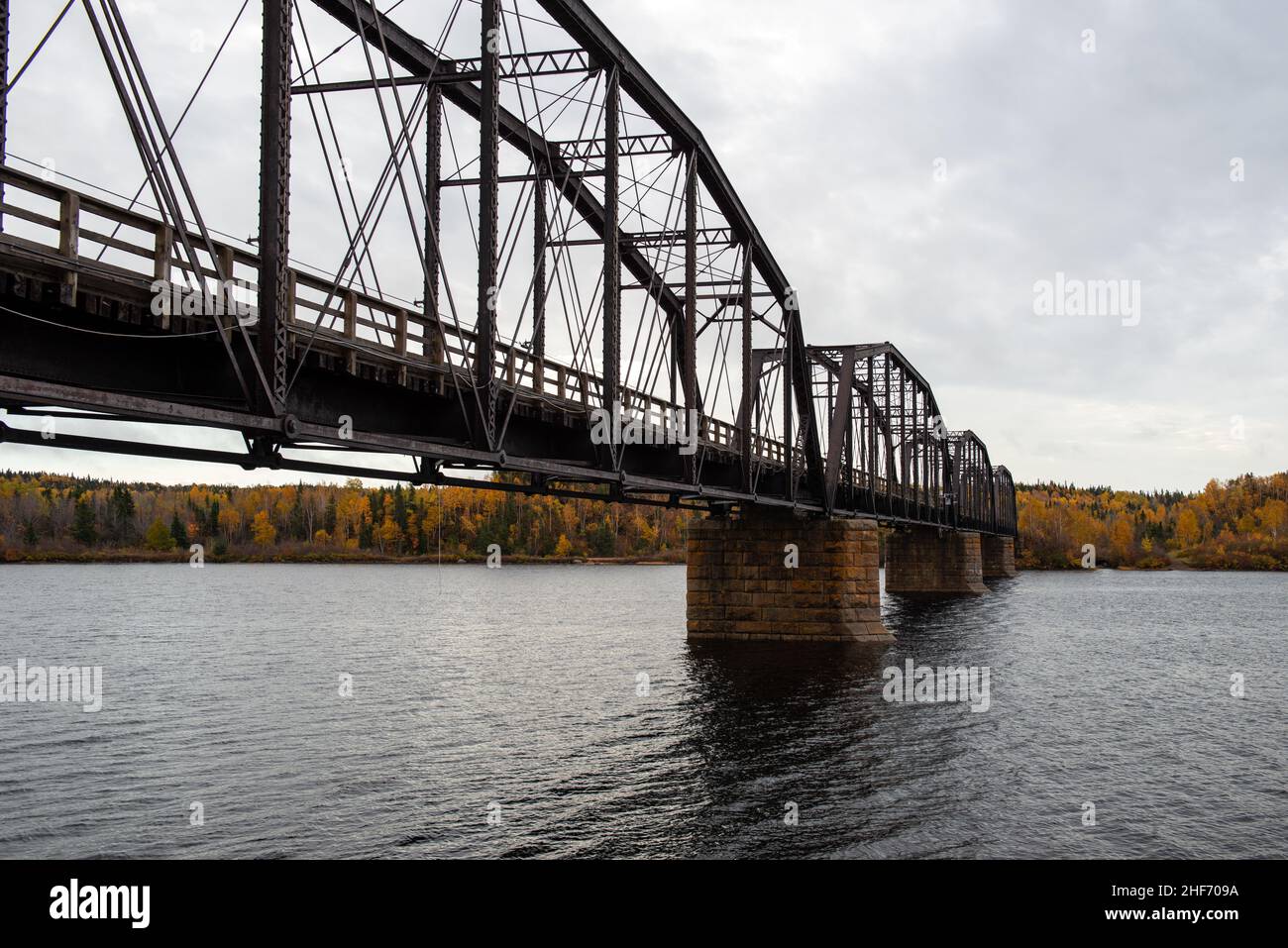 Stahlbrücke mit Holzdeck über einem großen Fluss in Neufundland. Die Brücke ist für Fußverkehr und ATV-Nutzung. Der Himmel ist klar blau. Stockfoto