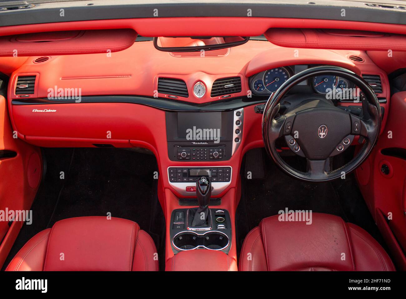 Ein Maserati GranCabrio aus dem Jahr 2011 mit Interieur aus rotem Leder und schwarzem Multifunktionslenkrad mit Daunendach an Einem sonnigen Tag in Manchester Stockfoto