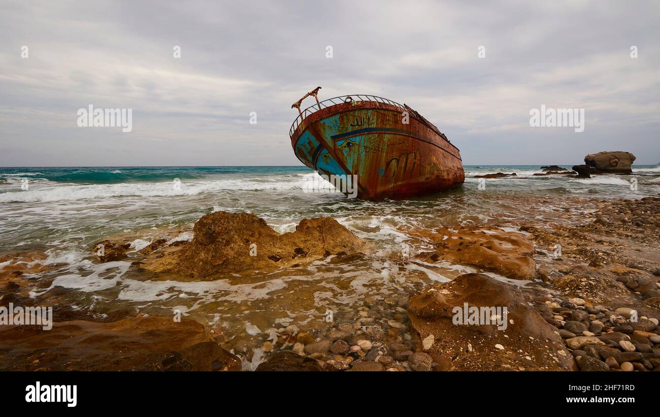 Griechenland, griechische Inseln, Ionische Inseln, Korfu, Westküste, Agios Gordios, schlechtes Wetter, wolkiger Himmel, Schiffswrack, Graffiti-Malerei, Surfen, Weitwinkel, im Vordergrund feste Küste und Meer, grauer Himmel, Wrack ist an der Küste Stockfoto