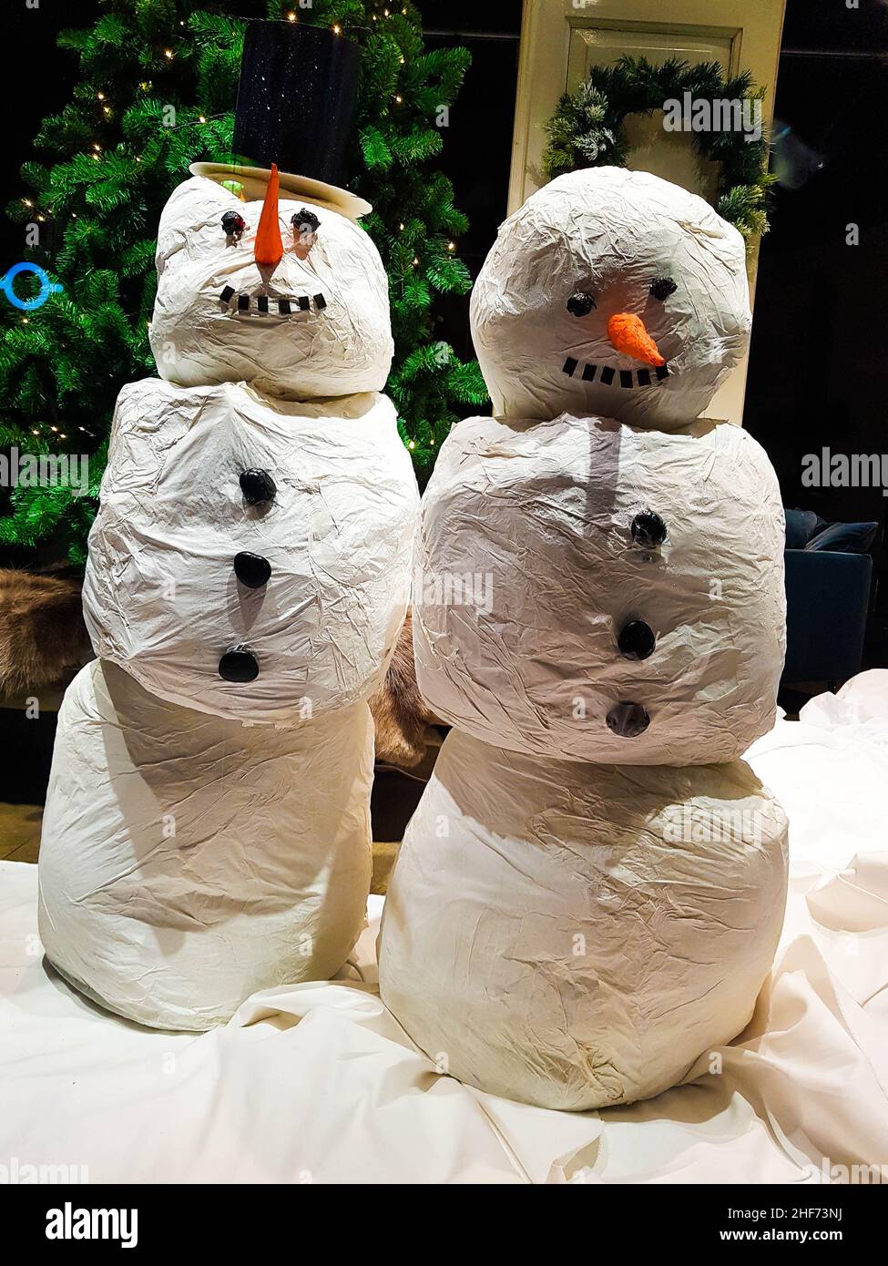 Zwei Schneemänner in Weiß mit einer Karottennase und Kohletasten in einem Schaufenster. Weihnachtsgrüße, frohe Weihnachten, Weihnachtskarte, Feiertag, Backgrou Stockfoto