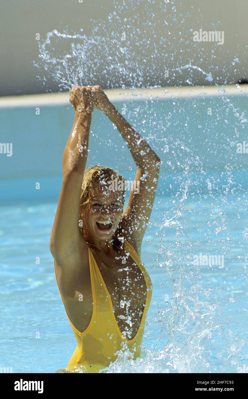 Attraktive blonde Haare junge Frau Schwimmbad natürlichen Körper lächelnd Springen mit Spritzern Stockfoto